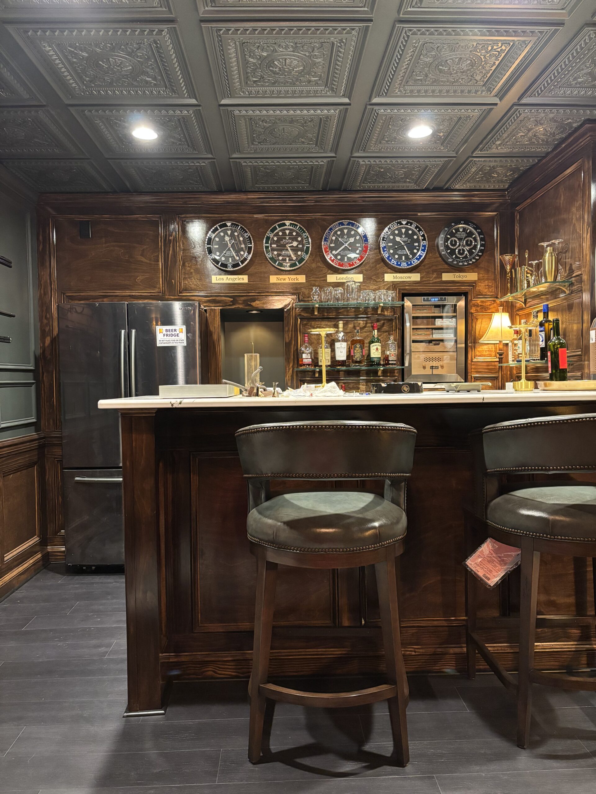 Finished basement bar with stools and tin ceiling