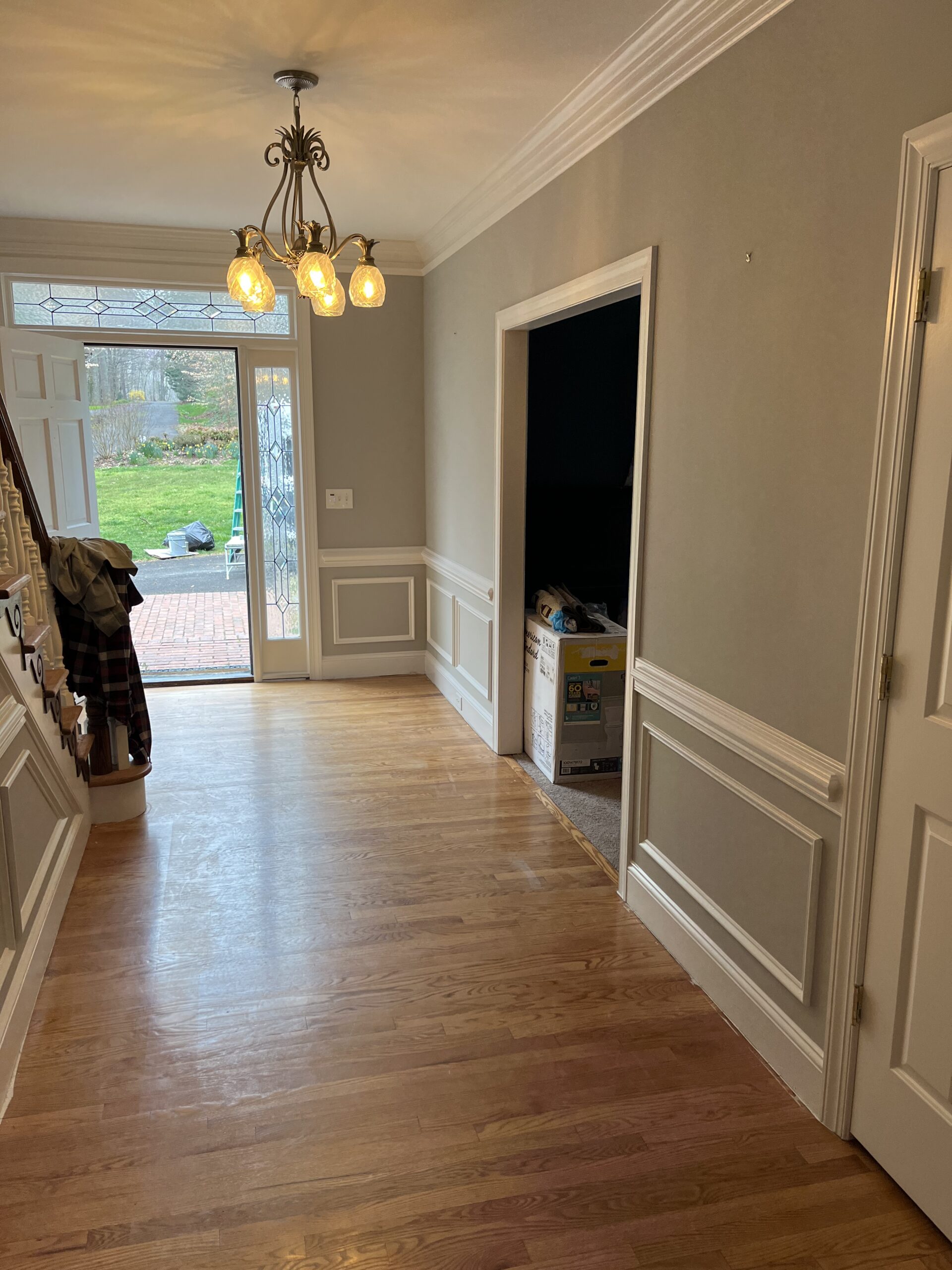 Freshly painted entry hall with hardwood floors and chandelier