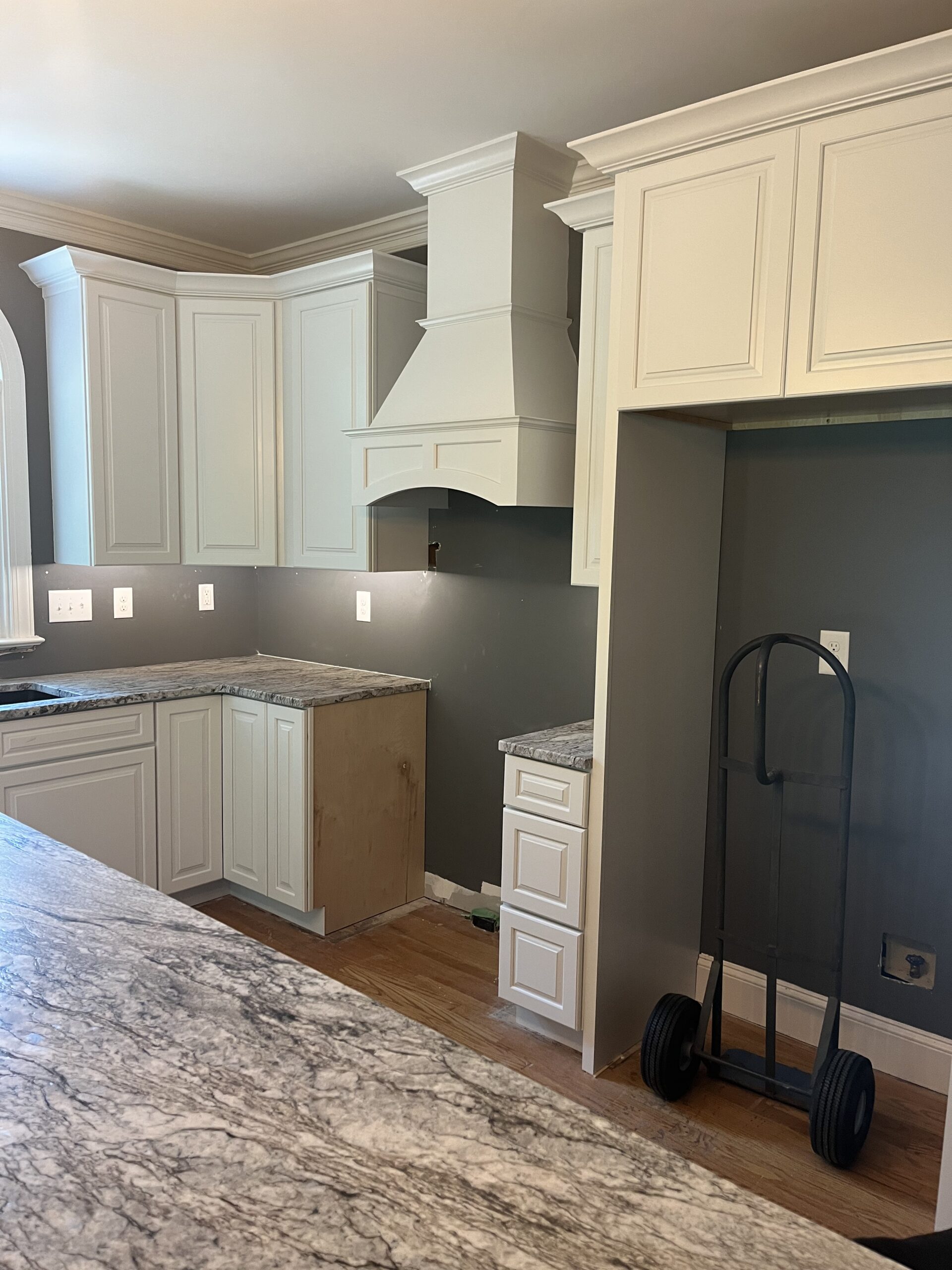 Kitchen with white cabinets, range hood and granite countertops